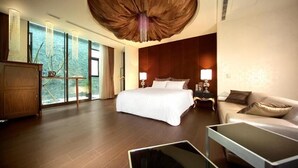 Una habitación de hotel moderna con una cama grande, un sofá, un escritorio y vistas al exterior.