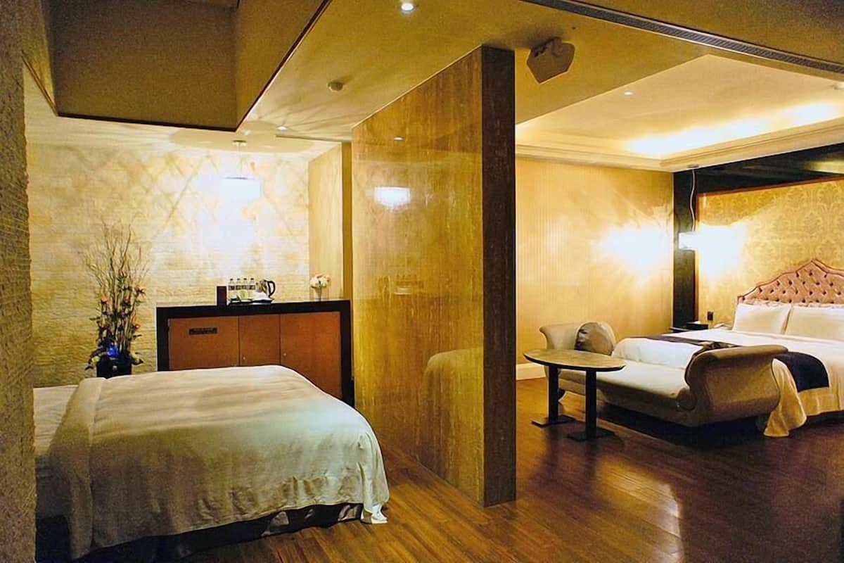 A hotel room with a bed, a sofa, a small table, and a desk with a lamp.