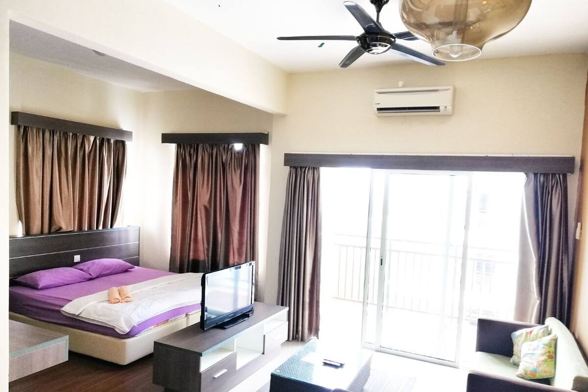 A modern hotel room with a bed, a TV, a ceiling fan, and a balcony with curtains.