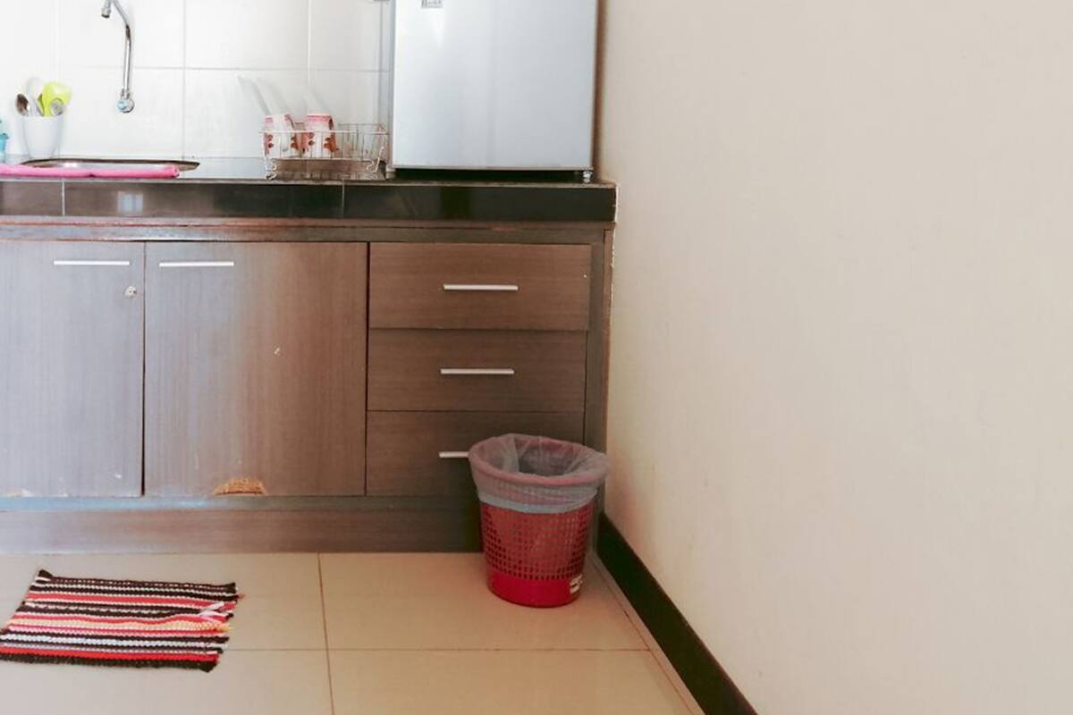 A small kitchen with a sink, a refrigerator, and a trash bin.
