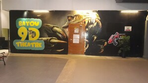 A theater entrance with a large dinosaur mural and a sign reading "Bayou 9D Theater". - Junikastay Blagoon Melaka (Malacca City)