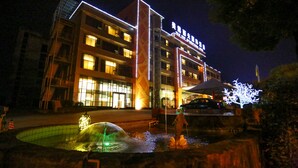 A hotel with multiple floors, outdoor lighting, and a water feature in the foreground. - Vilu Reef International Hotel (Zigong)