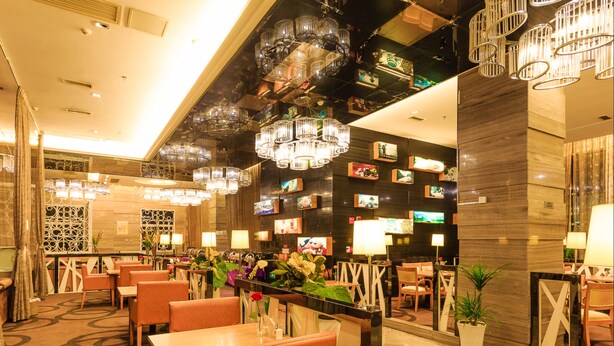 A hotel lobby with multiple seating areas, a reception desk, and a variety of wall decorations including framed pictures and televisions. - Vilu Reef International Hotel (Zigong)