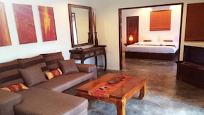 A modern living room with a brown sofa, a wooden coffee table, and a large mirror. - Sazana Villa Resort (Koh Samui)