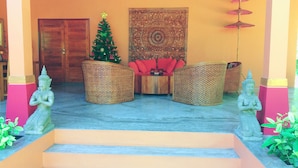 A reception area with a Christmas tree, a Buddha statue, and a traditional tapestry. - Sazana Villa Resort (Koh Samui)