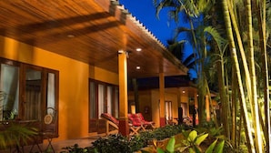 A resort with a covered outdoor area, lounge chairs, and tropical plants. - Sazana Villa Resort (Koh Samui)
