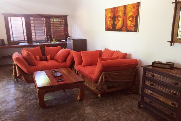 Una sala de estar con un sofá modular, una mesa de centro de madera y un aparador de madera oscura.