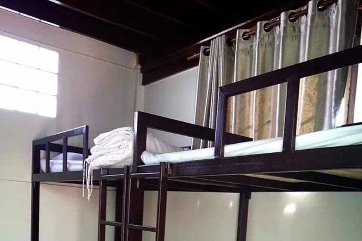 A bunk bed room with a ladder, a window with curtains, and a tiled floor.