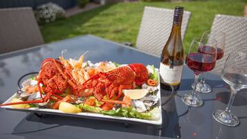 A lobster dish on a table with wine glasses and a bottle.