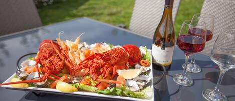 A lobster dish on a table with wine glasses and a bottle.