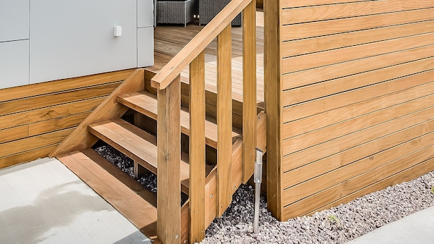 Un bâtiment moderne doté d’un escalier en bois menant à un espace extérieur couvert aménagé avec des sièges.