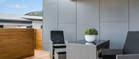 A modern outdoor seating area with wicker furniture and a potted plant.