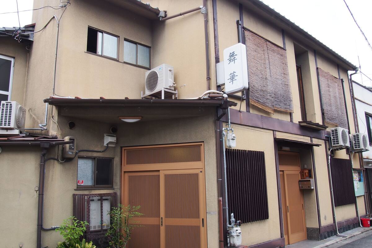A building with a traditional Japanese gate, air conditioning units, and a sign with Japanese characters.