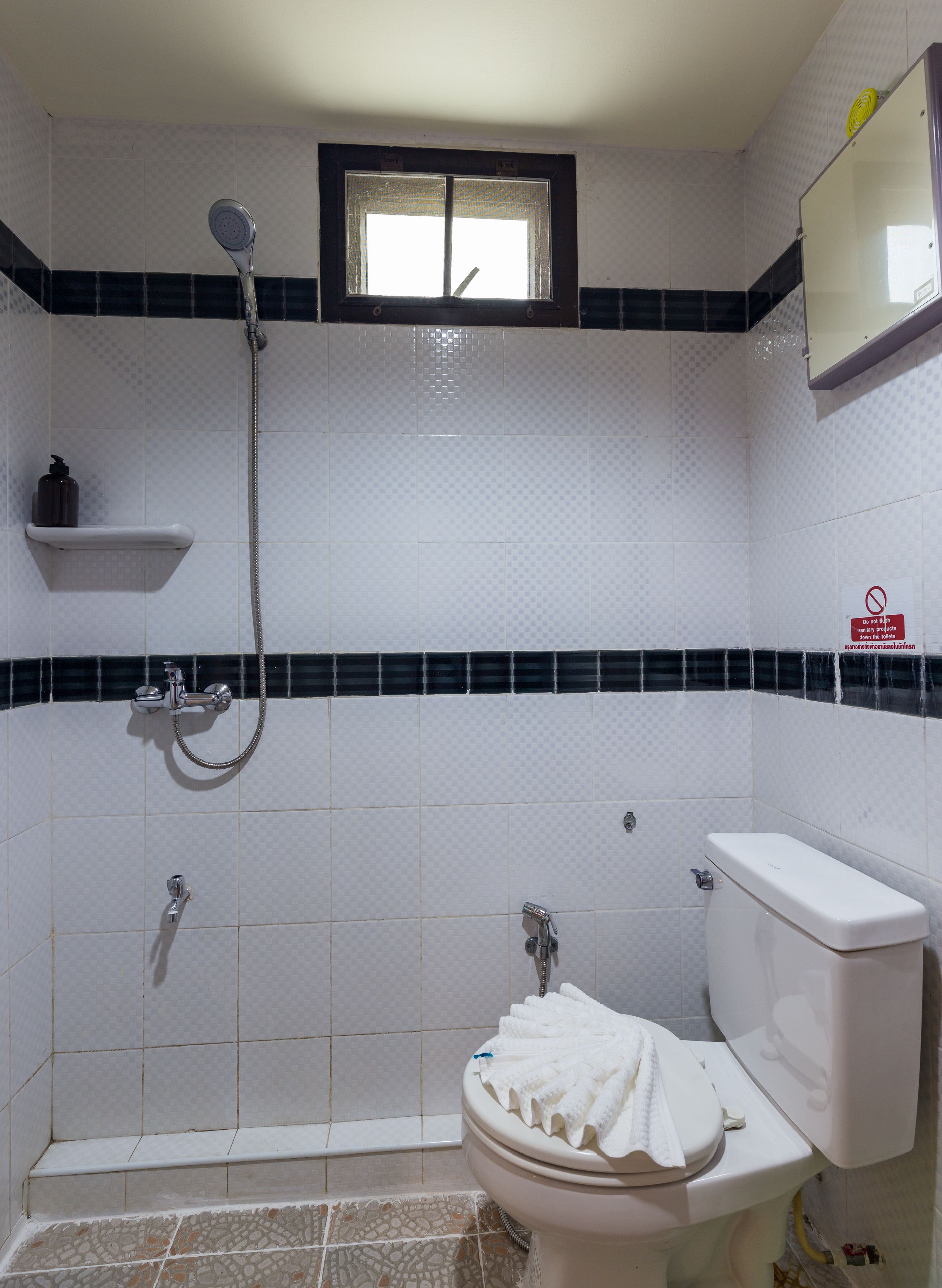 Une salle de bain avec une douche, des toilettes et une fenêtre.