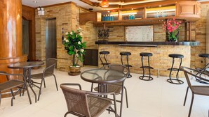 A restaurant with a brick wall, wooden bar counter, and multiple seating areas including round tables and bar stools. - P R Patong Hotel (Patong)