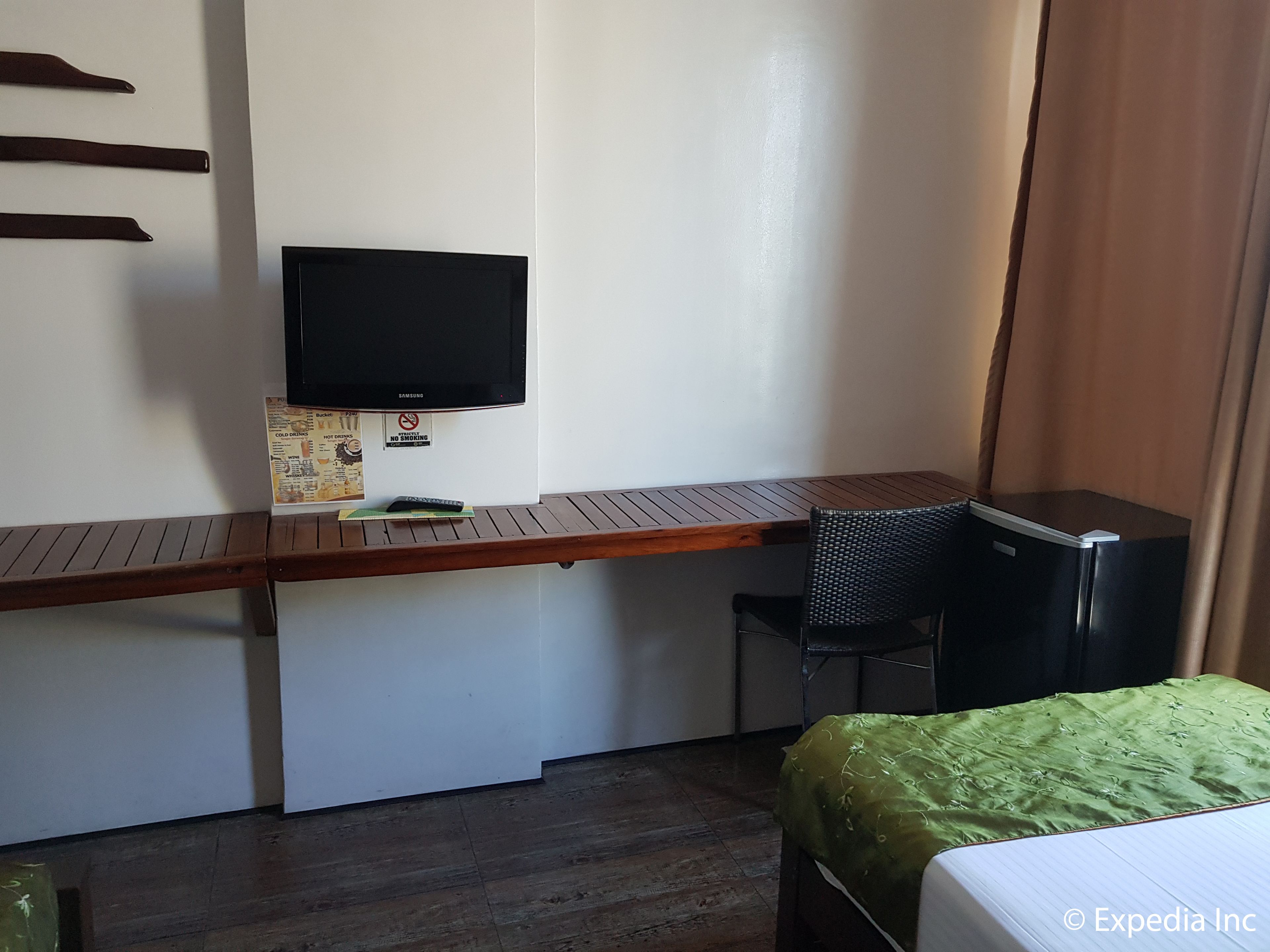 A hotel room with a desk, a television, a chair, and a bed.