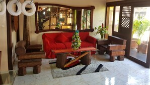Una sala de estar acogedora con un sofá rojo, una mesa de centro de madera y un árbol de Navidad.