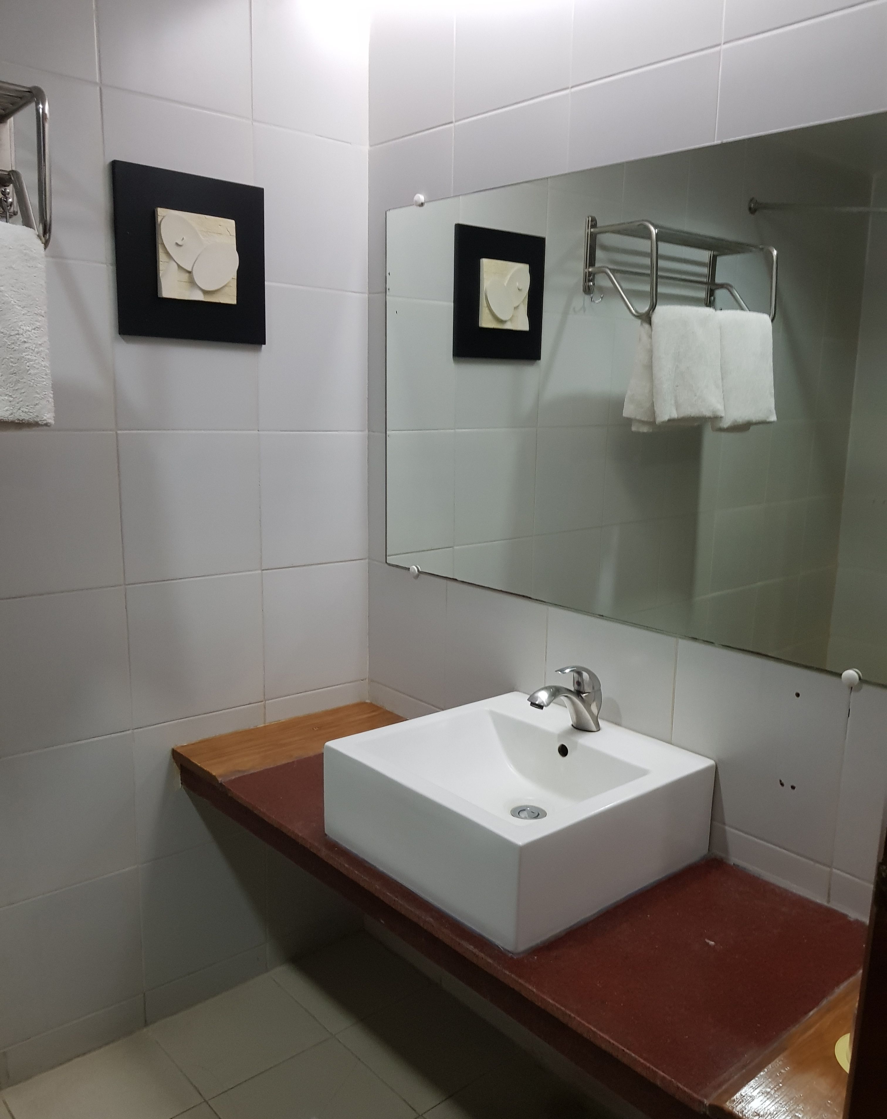 Une salle de bain avec un lavabo blanc, un miroir et un porte-serviettes.