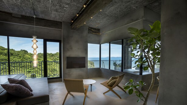 A modern interior with a large balcony, seating area, and a potted plant.