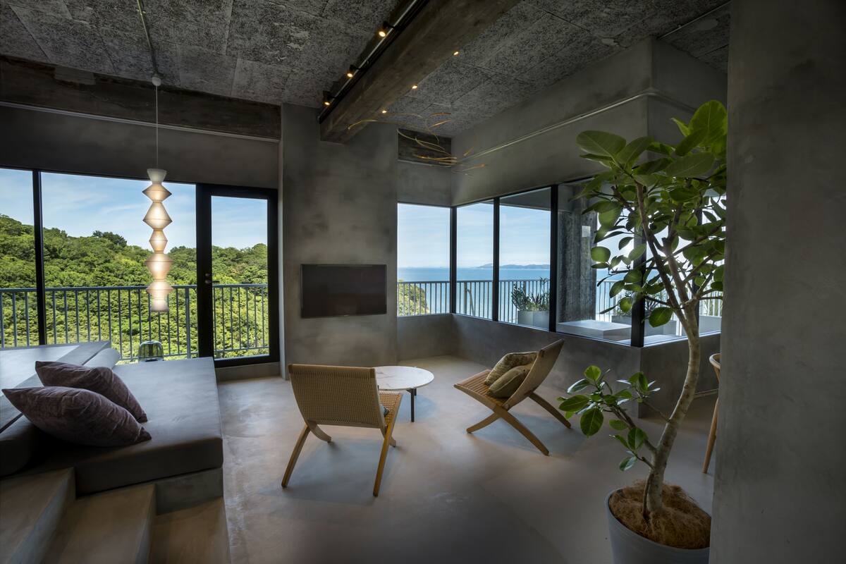 A modern interior with a large balcony, seating area, and a potted plant.