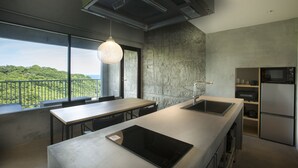 A modern kitchen with a large island, a built-in oven, and a view of a lush landscape.