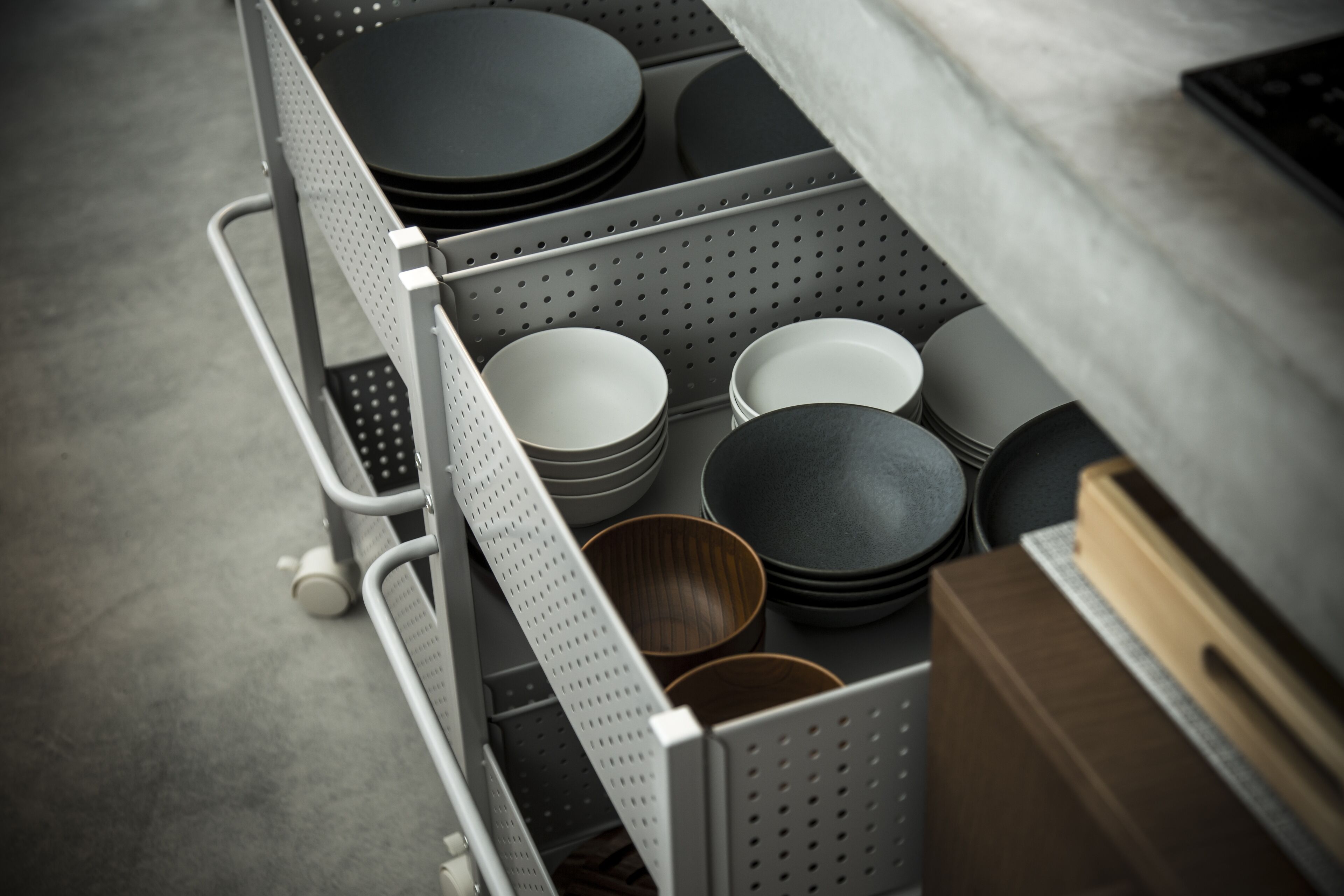 Un estante con diversos utensilios de cocina, incluyendo platos, cuencos y un bol de madera.