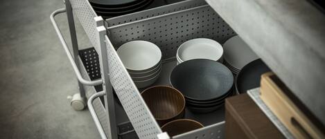 Un estante con diversos utensilios de cocina, incluyendo platos, cuencos y un bol de madera.