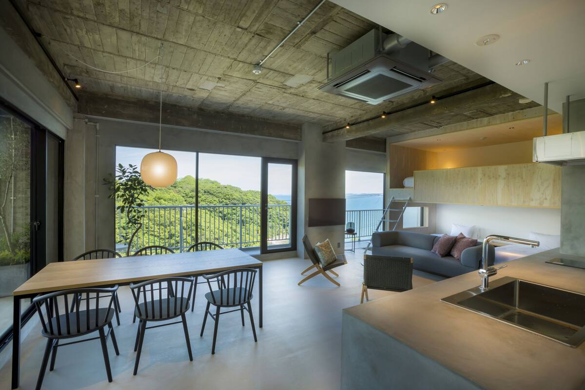 A modern kitchen with a large island, a dining area with chairs, and a sofa.