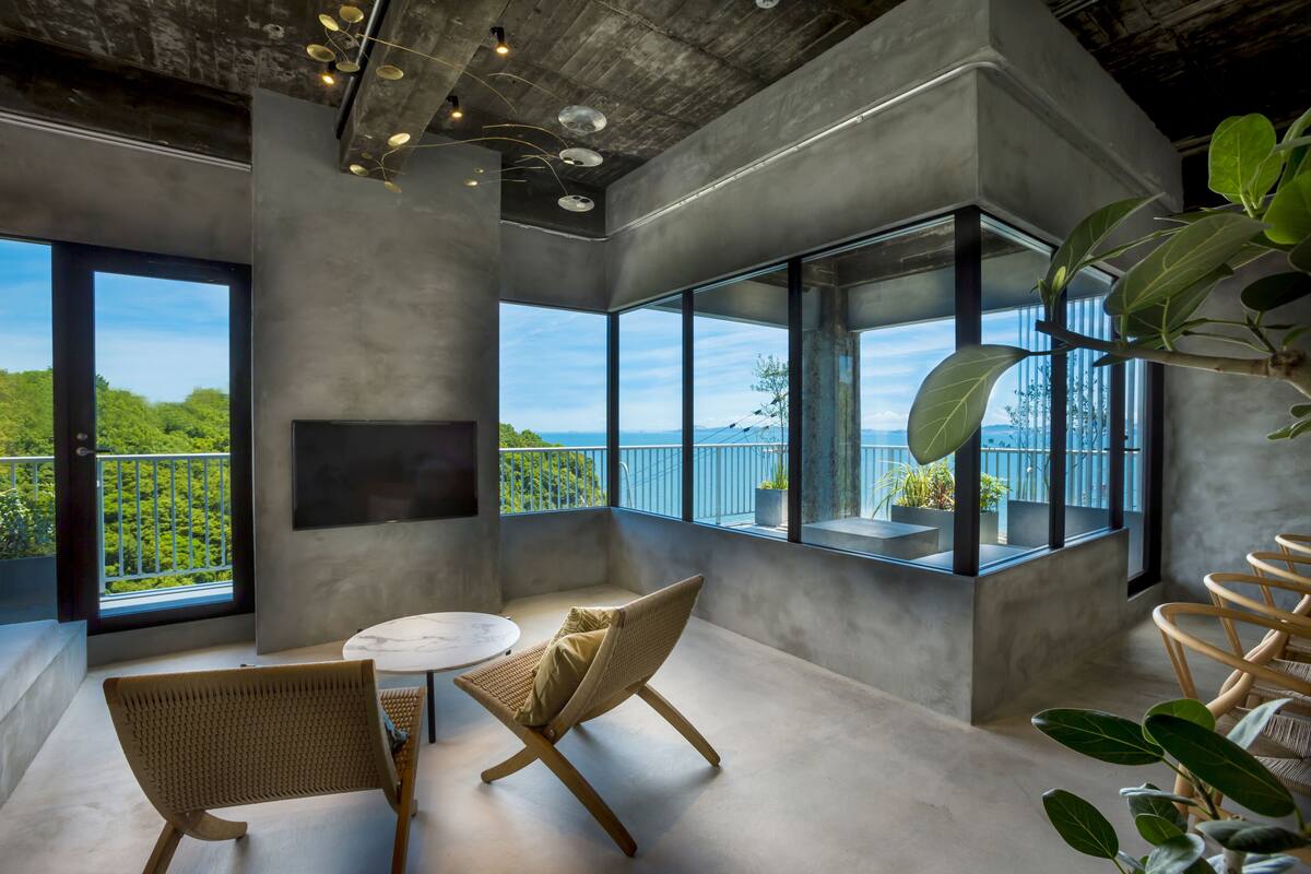 A modern interior with large windows, a round table, and wicker chairs.