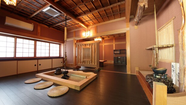 Una habitación japonesa tradicional con suelo de tatami, un biombó shoji, un área de asientos con esteras de tatami y techo de madera.