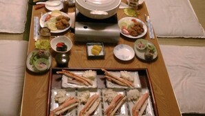 A long dining table with various dishes and a central pot, surrounded by tatami mats.