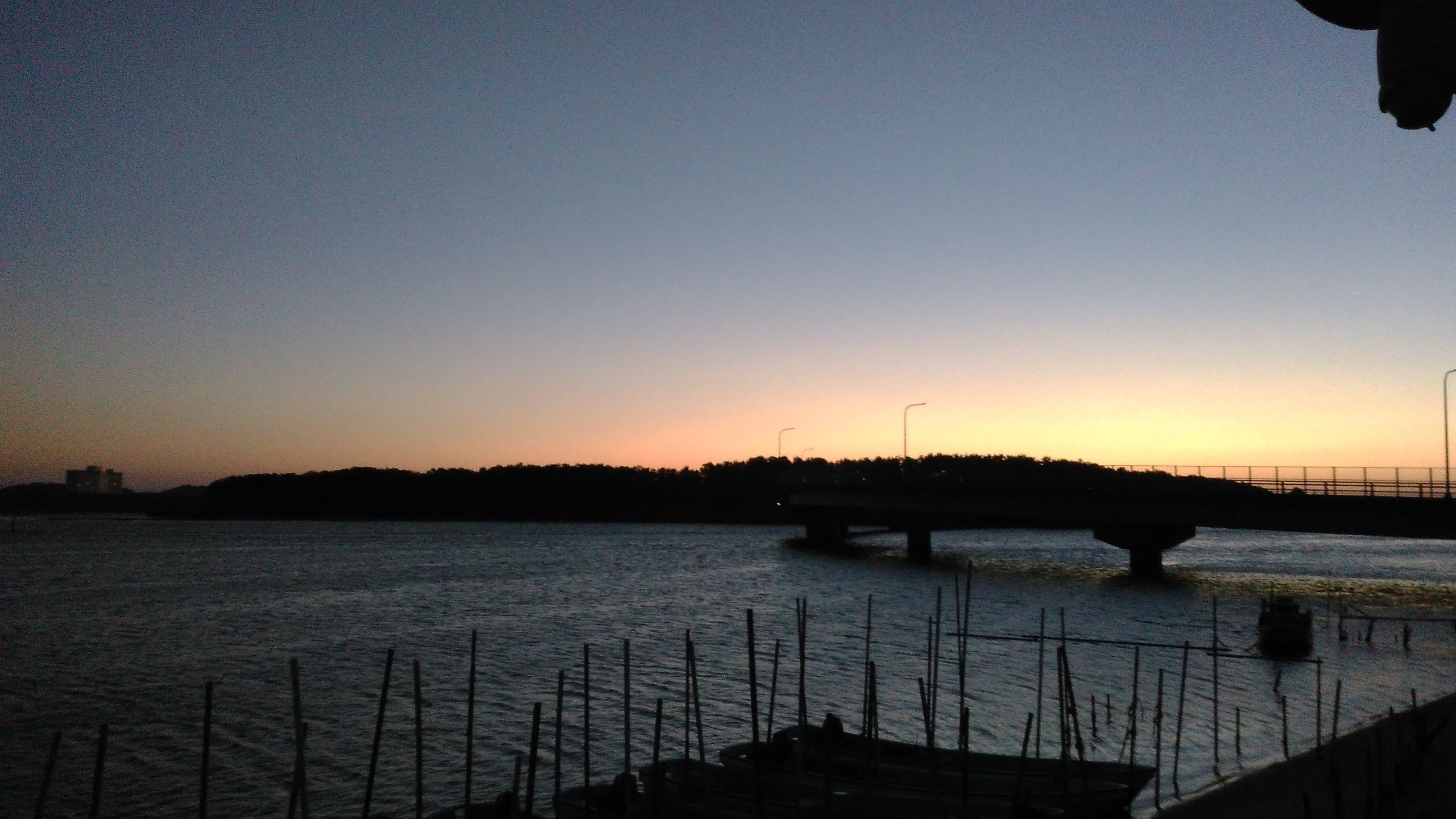 A bridge over a body of water with a sunset in the background.