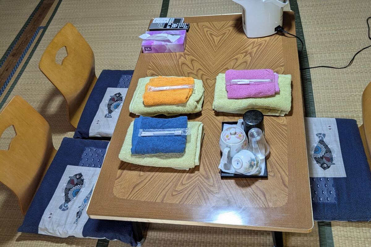 Ein traditioneller japanischer Raum mit Tatami-Böden, ein Holztisch gedeckt für Tee, mit Teekanne, Tassen und einer Tablett mit Teebeuteln.