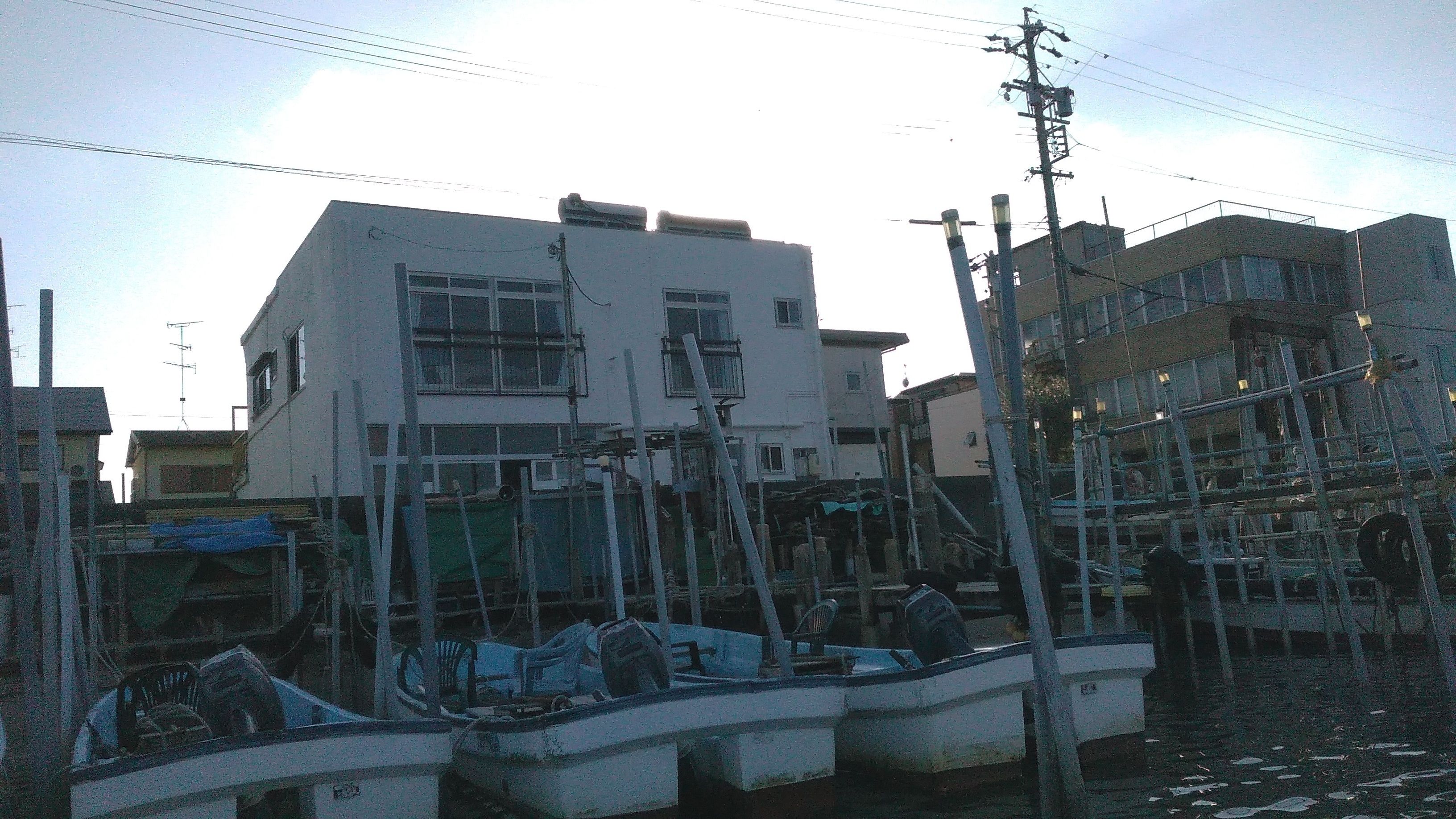 A building with a flat roof and multiple windows, surrounded by construction materials and scaffolding.