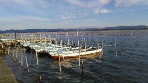 Uma marina com vários barcos atracados, um cais que se estende sobre a água e uma cadeia montanhosa ao longe.