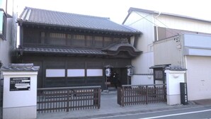 A traditional Japanese building with a tiled roof, wooden doors, and a gated entrance.