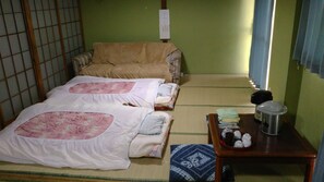 Une pièce de style japonais traditionnel, avec des tatamis au sol, un futon servant de lit, une petite table avec une théière et un paravent en papier de riz (shoji).
