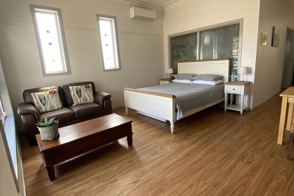 Ein Schlafzimmer mit einem Bett, einem Nachttisch, einem Holztisch, einer Couch und einem Deckenventilator.