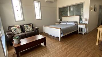 Une chambre à coucher comprenant un lit, une table de chevet, une table basse en bois, un canapé et un ventilateur de plafond.