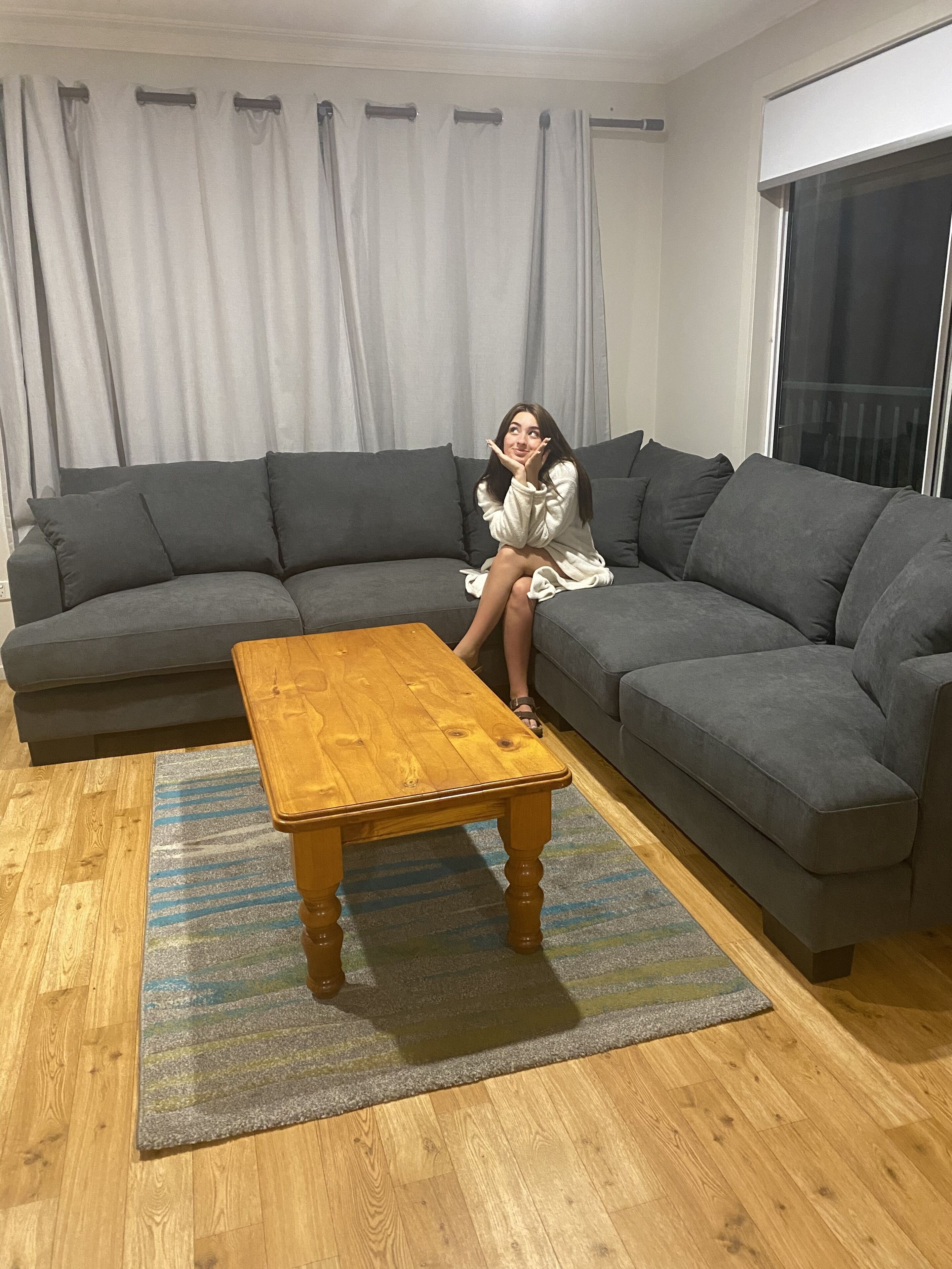 A living room with a grey sectional sofa, a wooden coffee table, and a striped rug.