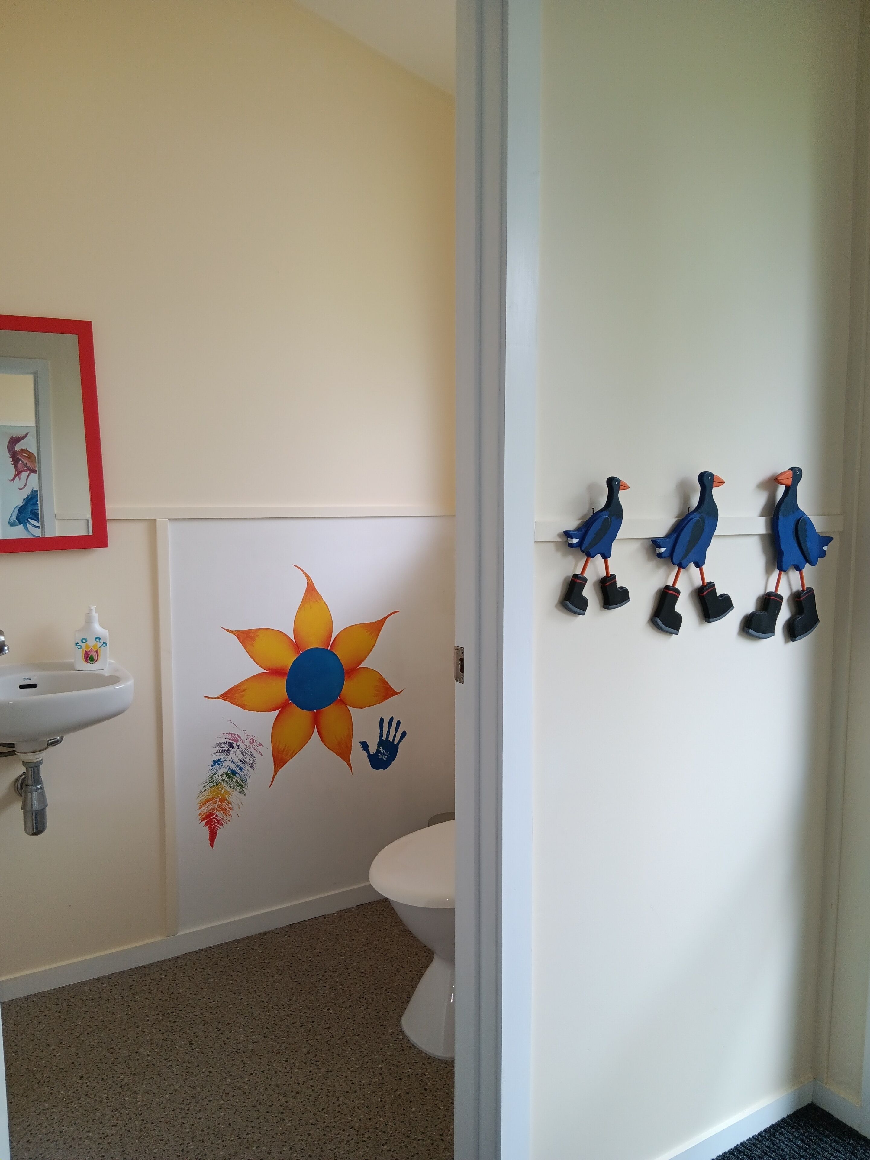 Un baño con lavamanos, inodoro, decoración en la pared y un espejo.