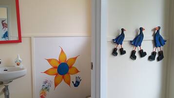 Un baño con lavamanos, inodoro, decoración en la pared y un espejo.