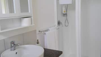 A bathroom with a white sink, a mirror, and a glass-enclosed shower.