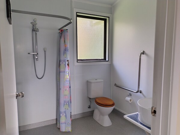 A bathroom with a shower, toilet, and sink. - Purple Hen Country Lodge (Tahawai)