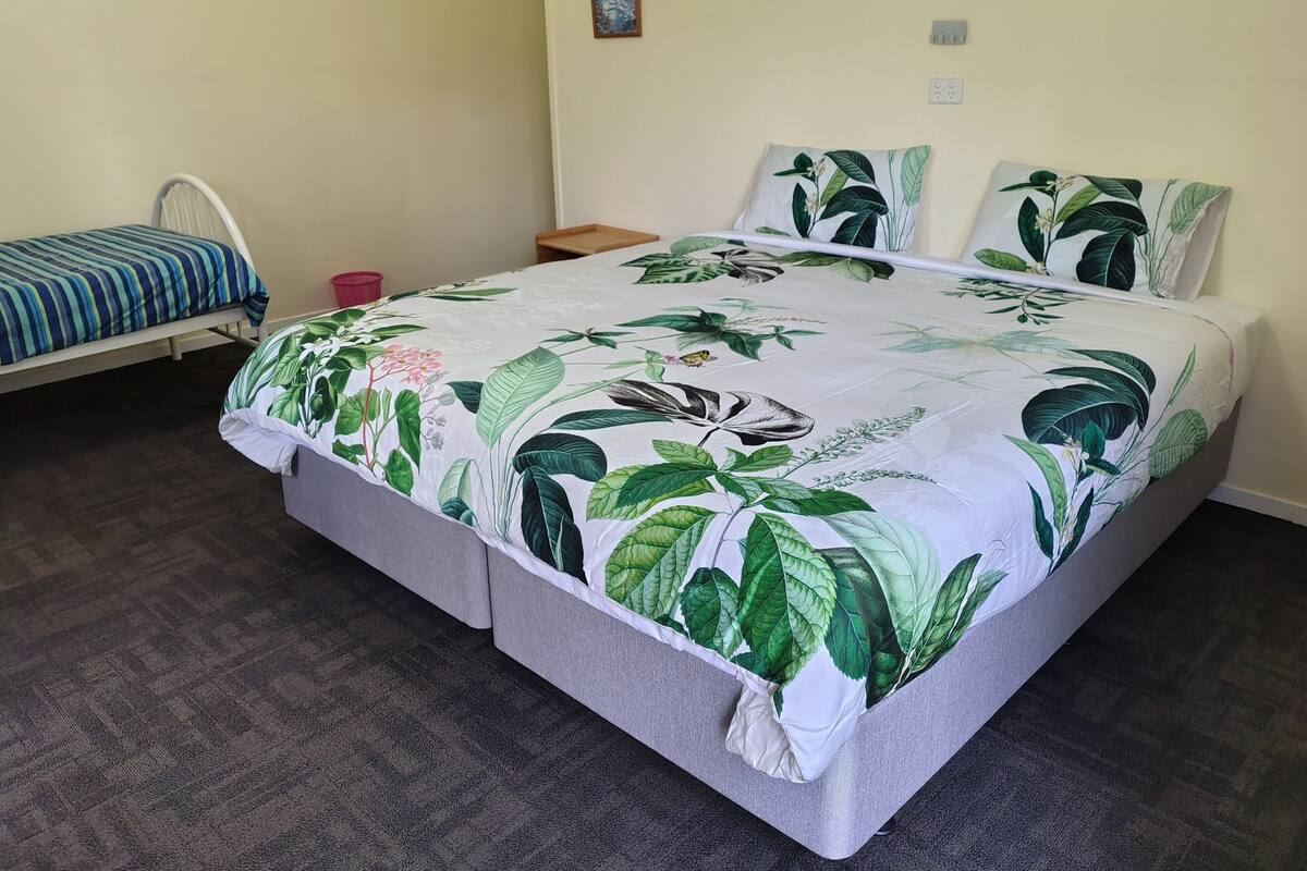 A bedroom with a large bed, a bedside table, a nightstand, and a small table.