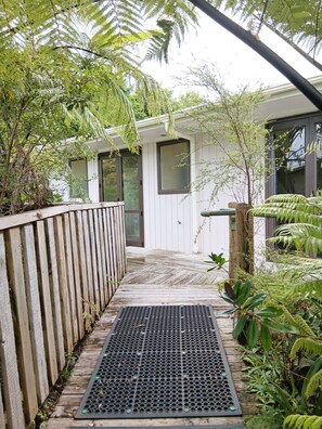 A wooden pathway leading to a building with a metal grate at the entrance. - Purple Hen Country Lodge (Tahawai)