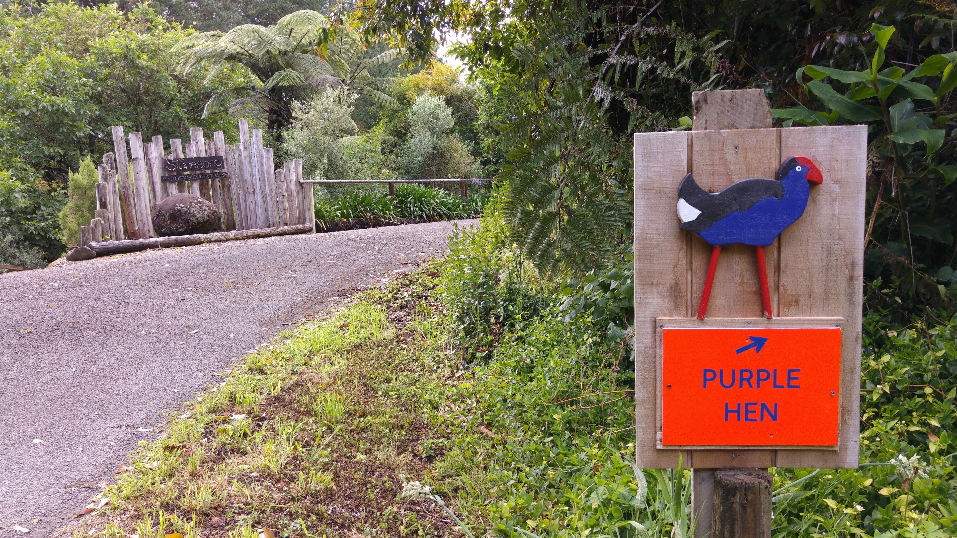 A wooden sign with a purple hen illustration and a sign below it that reads "PURPLE HEN".