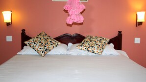Un lit bien fait, agrémenté d’oreillers à motifs, d’une tête de lit en bois et de deux lampes fixées au mur.