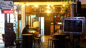 Un espace extérieur aménagé avec des tables et des chaises, un panneau affichant le menu et un panneau indiquant la présence d’un réseau Wi-Fi sur place.