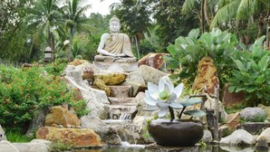 A serene garden with a Buddha statue, a pond, and lush greenery. - Qi Hotel and Club (Kota Kinabalu)